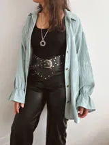 Sobrecamisa de muselina color verde pastel, con cuello camisero, mangas largas con puños fruncidos y volados, y corte oversize.