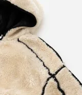 Campera de fleece color beige con diseño de paneles, costuras expuestas en color negro y cierre frontal. Posee cuello alto, mangas largas con puños elásticos y forro interior.
