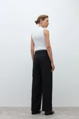 Pantalón de corte sastrero y pierna ancha, confeccionado en lyocell. Presenta pinzas en la cintura, cierre frontal con botón y bolsillos laterales. Incluye un cinturón fino de cuero con hebilla metálica.