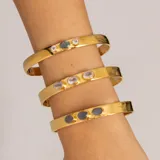 Brazalete rígido dorado con tres piedras ovaladas de cuarzo rosado.