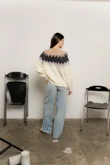 Sweater de punto color crudo con diseño de guardas geométricas en tonos negro, gris y beige en la parte superior.