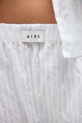 Short de pijama blanco con textura a rayas sutiles, cintura elástica con etiqueta de la marca y detalle de volados en el ruedo.