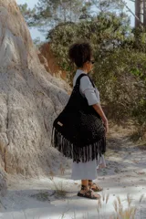 Bolso de mano grande tipo tote bag, tejido en crochet con técnica de trapillo reciclado. Presenta un diseño de punto grueso y flecos largos en el borde inferior.