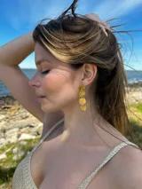 Aros colgantes dorados con diseño irregular en forma de cascada.