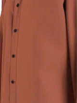 Camisa color ladrillo de corte relaxed, confeccionada en sarga de algodón elástico. Tiene cuello en punta, cierre de botones, puños redondos y bajo recto.