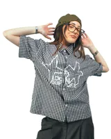 Camisa de manga corta con cuello, confeccionada en algodón con estampado de cuadros vichy en blanco y negro. Presenta un estampado serigrafiado en el frente con un logo abstracto y el texto "Local Support".