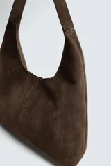 Bolso de hombro marrón con efecto serraje. Tiene un compartimento principal con cierre magnético y un bolsillo interior con cremallera. El asa es del mismo material.
