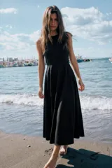 Vestido midi negro con cuello halter y falda acampanada con volumen.