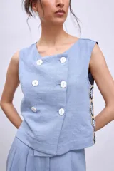Chaleco celeste con diseño cruzado y doble botonadura, sin mangas y con apliques de encaje en los laterales.