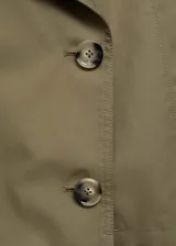 Chaqueta corta de estilo trench con cuello de solapa y cierre frontal de doble botonadura. Presenta diseño recto, manga larga y bolsillos laterales, confeccionada en tejido de mezcla de algodón con forro interior.