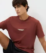 Remera de algodón color bordó, con cuello redondo, manga corta y corte comfort. Presenta un estampado localizado en el pecho con el texto 'The Pathfinders Movement'.