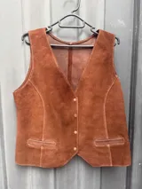 Chaleco sastrero de cuero con efecto desgastado, escote en V, cierre frontal con botones metálicos dorados y bolsillos frontales con solapa.