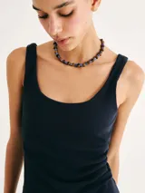 Musculosa de tela acanalada con cuello redondo y pliegues laterales que aportan textura y un ajuste entallado al cuerpo.