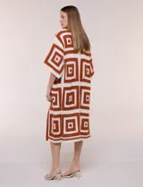 Cardigan largo confeccionado en tejido de punto calado estilo crochet, de color amarillo y blanco, con diseño geométrico de cuadrados, mangas amplias tipo kimono y corte abierto al frente.