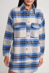 Chaqueta tipo camisa a cuadros color beige, azul y negro, con cuello clásico, cierre frontal con botones, mangas largas y dos bolsillos con solapa en el pecho.