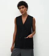 Chaleco alargado negro de punto en modelo recto con doble botonadura frontal de cuatro botones grandes, dos bolsillos delanteros aplicados y sisas amplias.