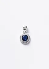 Dije circular estilo Lady Di, confeccionado en plata 925 con una zirconia central de color azul intenso rodeada por un halo de pequeñas zirconias blancas.