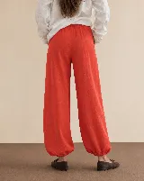 Pantalón rojo de corte holgado, estilo bombacho, con puños fruncidos en los tobillos.