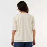 Camiseta de encaje color beige con diseño calado, escote en V y mangas cortas abullonadas.