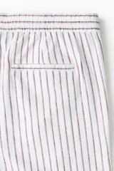 Short de lino y viscosa, color blanco con rayas verticales delgadas, corte relajado, cintura elástica con cordón de ajuste y bolsillos laterales.