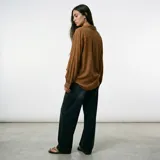 Blusa de color marrón con cuello camisero, cierre frontal de botones y mangas largas abullonadas con puños ajustados.