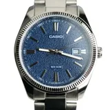 Reloj Casio de acero inoxidable con caja redonda de 38 mm y malla plateada. Presenta una esfera azul con acabado texturizado, índices y manecillas plateadas, y ventana de fecha a las 3.