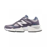 Championes urbanos New Balance modelo 9060, con diseño robusto y futurista en tonos violeta, gris y blanco. Presentan una combinación de materiales en gamuza y malla, con el logo N característico en los laterales y una suela gruesa con tecnología de amortiguación.