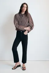 Jeans de tiro alto con cinco bolsillos, diseño cropped flare y bajo sin costuras. Cuenta con cierre frontal de cremallera y botón metálico.