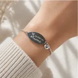 Pulsera de plata 925 con cadena de eslabones finos y chapa ovalada central con la inscripción grabada 'Te quiero Mamá'. Incluye un pequeño dije colgante en forma de corazón.