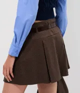 Short pollera de corte sastrero con estampado a cuadros, diseño con pliegues frontales, cintura estructurada con pasadores y cinturón incluido.