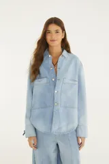 Camisa de jean de corte amplio con cuello camisero, cierre frontal con botones metálicos y grandes bolsillos frontales con solapa.