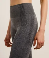 Legging deportiva de tiro alto confeccionada en tejido seamless color gris melange. Presenta un diseño ajustado con paneles texturizados en los laterales que ofrecen un efecto modelador y levanta pompis.