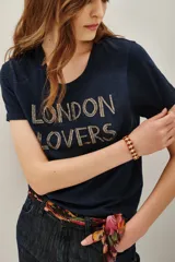 Remera azul marino de algodón con cuello redondo y mangas cortas. Presenta la frase 'LONDON LOVERS' bordada en el frente con cuentas metálicas.