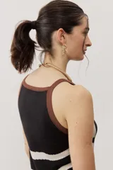 Vestido largo de punto con diseño geométrico y de ondas en color negro y crudo, sin mangas, con escote halter y detalle de flecos en el ruedo.
