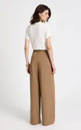 Pantalón sastrero de tiro alto en color camel, con corte recto y pernera ancha. Presenta pliegues frontales, bolsillos laterales y cierre frontal con cremallera y gancho. Incluye un cinturón a juego con hebilla metálica ovalada.