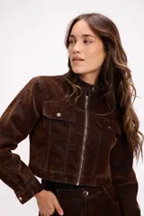 Chaqueta estructurada de efecto desgastado en tonos marrón y negro con sutiles matices celestes. Presenta cuello mao, cierre frontal metálico, bolsillos frontales con tapa y botón, y puños abotonados.