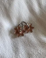 Aros tipo argolla dorada con dije colgante en forma de estrella de acrílico color rosa.