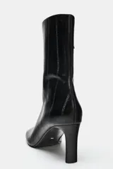 Botín de piel de color negro con textura efecto animal print, tacón fino y punta cuadrada.