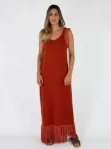 Vestido largo negro de punto con tirantes anchos rayados en tonos marrones y amarillos, escote redondo y flecos multicolor en el ruedo.