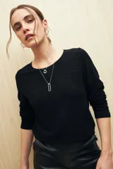 Top negro de manga larga con textura metalizada y acabado glitter.