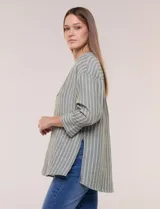 Blusa de silueta holgada a rayas verdes y blancas, confeccionada en tela liviana con textura arrugada. Presenta cuello en V profundo con botones frontales, mangas 3/4 de hombro caído y ruedo asimétrico con aberturas laterales.