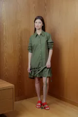 Vestido camisero corto color verde oliva con botones frontales, cinturón trenzado y volados en el ruedo.