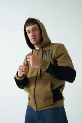Campera de felpa de diseño color block en tonos marrón y negro, con capucha con cordón ajustable, cierre frontal y bolsillos. Presenta lettering estampado en el pecho.
