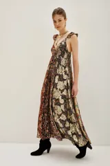 Vestido largo con escote en V profundo y tirantes con volados. Presenta un diseño patchwork con diferentes estampados florales y texturas en tonos tierra, negro y dorado metalizado.