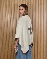 Ruana tejida de algodón color beige con terminaciones y cuello en marrón, y diseño de estrella en la espalda.