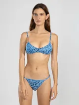 Top de bikini con estampado animal print en tonos celeste y azul, con breteles finos regulables y detalle de argolla dorada en uno de los breteles.
