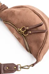 Cartera tipo bandolera de gamuza sintética color marrón, con diseño de media luna, cierre frontal con doble tirador metálico y detalle de borla lateral.