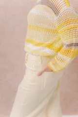 Buzo tejido de punto calado con rayas horizontales multicolor en tonos azul, amarillo, celeste y blanco, con escote bote, mangas largas y hombros caídos. Incluye top básico al tono.