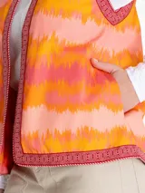 Chaleco sin mangas estilo boho, con estampado de ondas en tonos naranja, rosado y amarillo. Presenta bordes con detalles geométricos en color bordó y cierre frontal abierto.