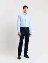 Ambo de vestir compuesto por camisa de manga larga en color celeste y pantalón de vestir en color azul marino. La camisa presenta cuello clásico y cierre frontal con botones, mientras que el pantalón es de corte recto y se combina con un cinturón negro.